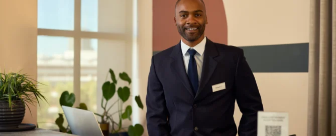 Cheerful Professional Man Standing at Reception Desk Indoors