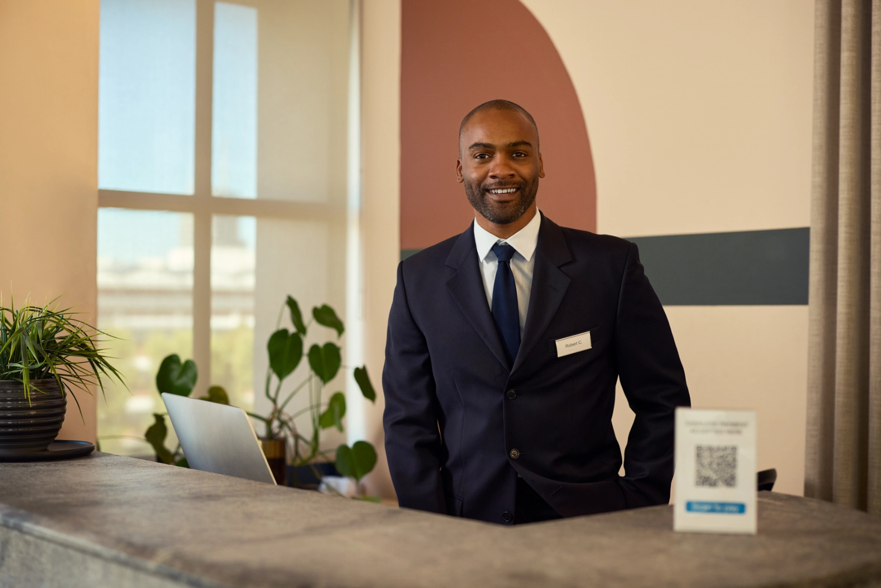 Cheerful Professional Man Standing at Reception Desk Indoors