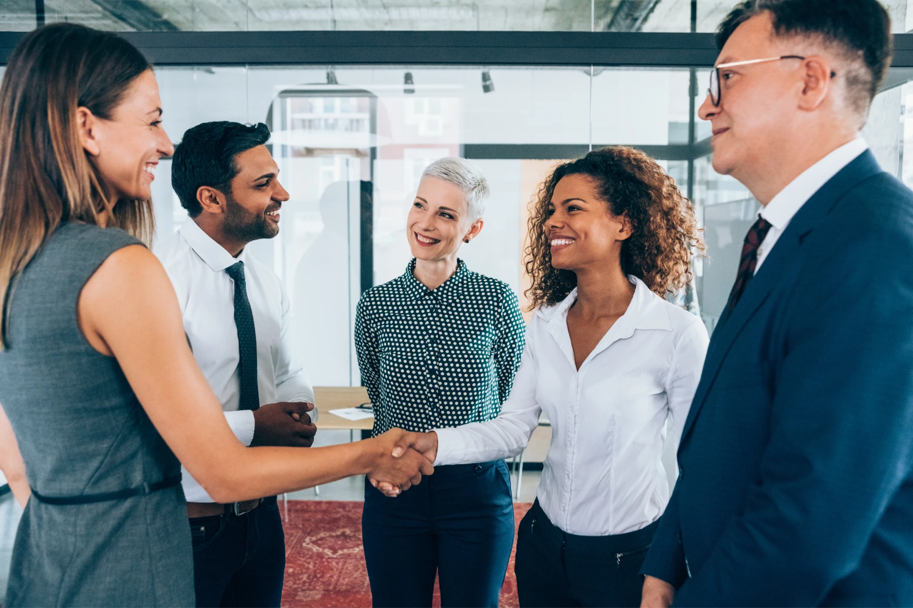 Corporate hospitality professionals shaking hands during a workplace introduction in a modern office setting